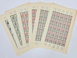 quatre vieux timbres représentant des personnes, sur une feuille de papier posée sur une surface blanche