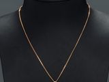 a gold necklace with a cross pendant on a mannequin neck