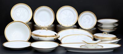 de nombreuses assiettes et bols blancs et dorés sur la table