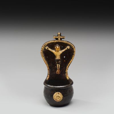 une figurine noire et dorée sur laquelle est représenté un crucifix