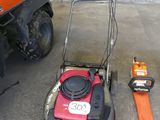 a lawn mower and a chainsaw on the ground