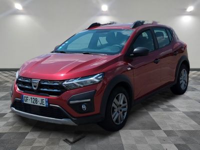 La voiture rouge est garée sur un sol à damier, dans une pièce.