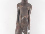 an old wooden statue of a man standing with his hands in his pockets