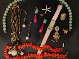 a necklace, bracelet, watch, and other jewelry laid out on a black surface