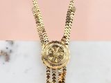 a gold necklace with a medallion and tassels on a marble surface