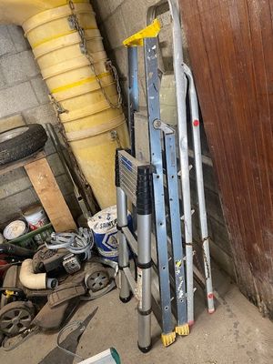 a ladder leaning against a wall next to a pile of tools