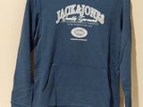 le dos d'un sweat-shirt bleu suspendu à un cintre accroché au mur