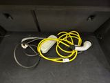 a car trunk with a yellow hose and a charger in it