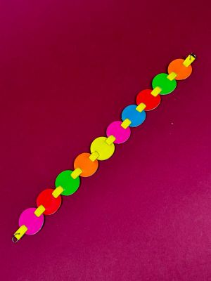 a close up of a rainbow colored bracelet on a pink surface