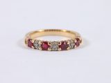 a close up of a yellow gold ring with red and white stones