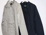 two jackets hanging on a clothes rack in a white room