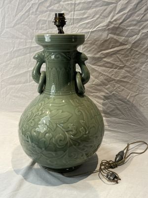 un vase vert avec une lampe posée sur une table blanche