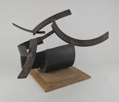 une photo d'une sculpture en métal et en bois posée sur un socle en bois