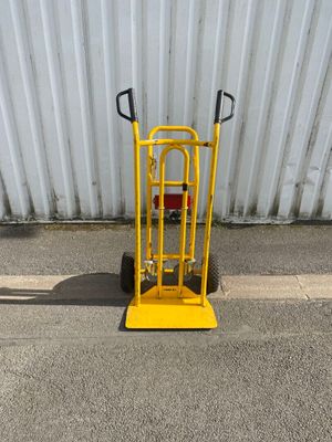 un diable jaune avec une poignée jaune dans la rue