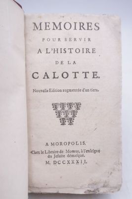 an old book sitting on top of a white table next to a cup