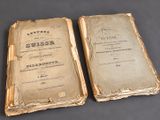 two old books sitting on top of a table next to each other