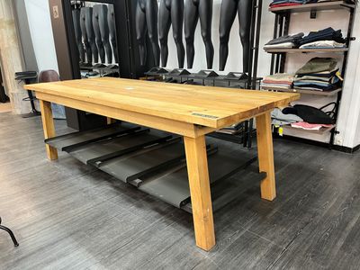 une table en bois dans une pièce où de nombreuses paires de chaussures sont accrochées au mur