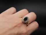 a woman ' s hand holding a black and white diamond ring