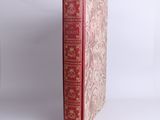 un vieux livre à la couverture rouge posé sur une table blanche