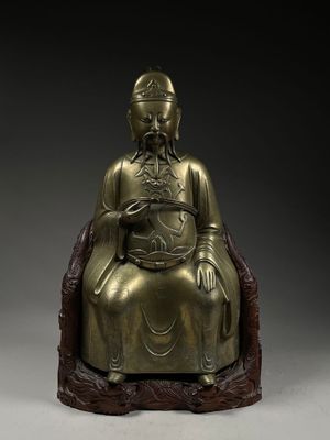 a bronze figure of a seated buddha on a rock