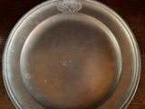 a silver plate sitting on top of a wooden table next to a knife and fork
