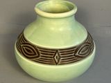 un vase vert orné d'un motif marron