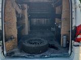 the back of a white van with the door open and a tire in the back