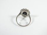 a close up of a ring on a white surface with a black stone
