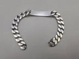 silver plated bracelet with a clasp on a gray surface