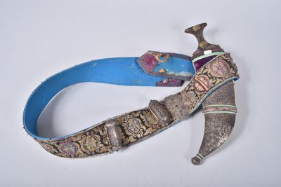 une ceinture bleue ornée d'un couteau, posée sur un fond blanc
