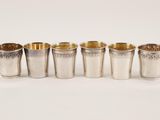 a set of six silver cups with gold rims on a white background