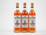 trois bouteilles de vin posées les unes à côté des autres sur une surface blanche