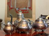 a silver tea set sitting on a table in front of a painting