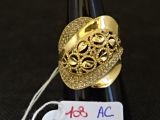 une bague en or posée sur une bouteille de vin à laquelle est accrochée une étiquette de prix