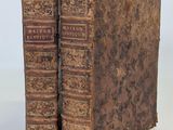 deux vieux livres posés l'un sur l'autre sur une surface blanche
