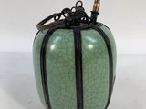 green and black cracky vase with a bamboo stick in it