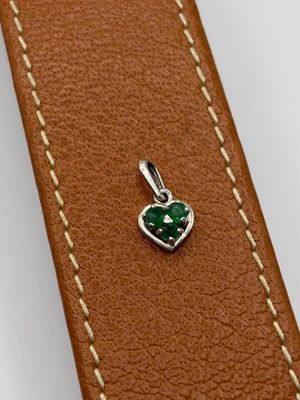 a close up of a leather strap with a green heart charm