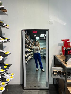 une femme en train de se prendre en photo dans un miroir dans un magasin de chaussures