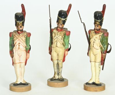three figurines of soldiers with weapons and uniforms on wooden bases