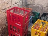 bottles and crates of soda are lined up against a brick wall