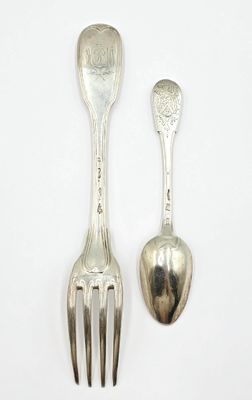 deux cuillères et une fourchette en argent sur une surface blanche