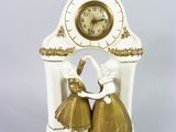 a white clock with a gold decoration on top of it