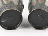 pair of silver vases with floral designs on them on a white surface