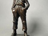 a bronze statue of a boy standing on a base with his hands in his pockets