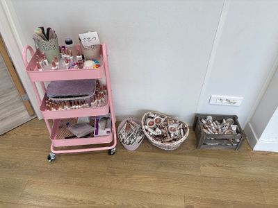 a pink cart that is next to a wall with a lot of stuff on it