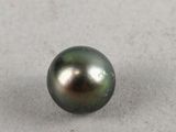a close up of a black pearl on a white surface