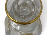a clear glass jar with a gold rim on a white surface