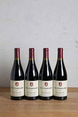 four bottles of red wine are lined up on a wooden table