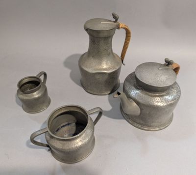 une théière en argent et deux tasses posées sur une table blanche