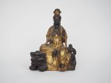 une statue en or représentant un homme assis sur un rocher avec un chien